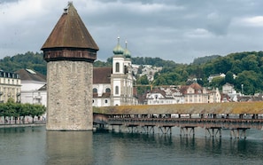 Una torre di pietra storica, una chiesa con cupole e un ponte sull'acqua.