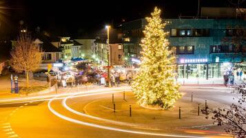 Ein Weihnachtsbaum auf einem Marktplatz mit einer Kreisverkehr und Gebäuden im Hintergrund.
