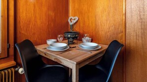 Una mesa de comedor de madera con dos sillas, un objeto decorativo con forma de corazón y dos copas de vino.