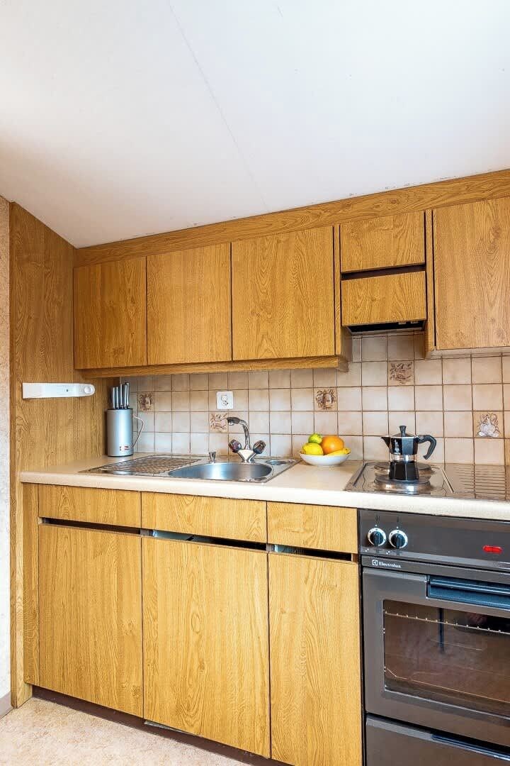 Eine Küche mit Holzausstattung, einem Edelstahlspülbecken, einem Wasserkocher und einer Obstschale.