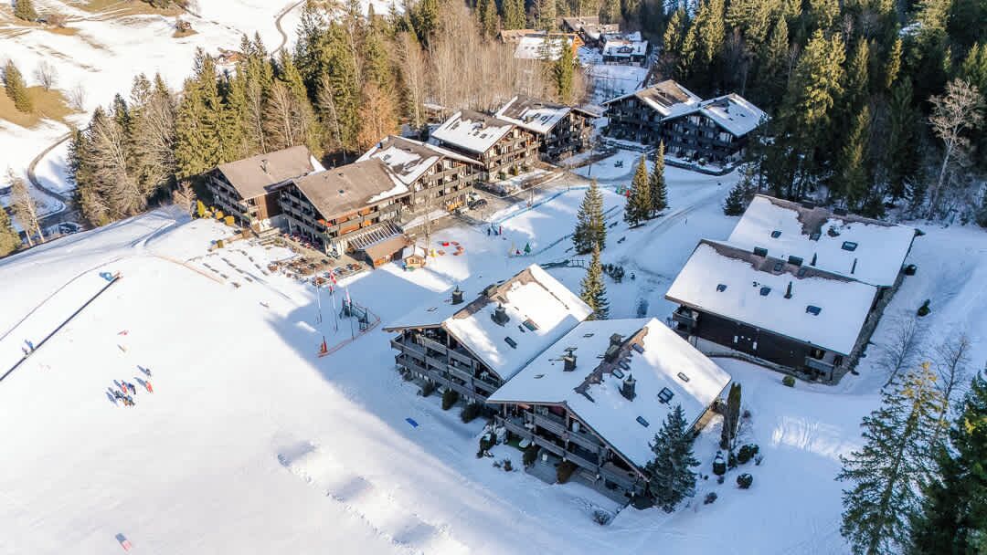 Ein Skigebiet mit mehreren Berghütten, Skipisten und einem Parkplatz.