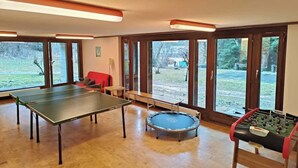 Une pièce spacieuse équipée d’une table de ping-pong, d’un baby-foot et d’un trampoline.