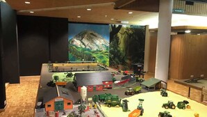 Une maquette détaillée d’une ferme, comprenant différents bâtiments, véhicules et figurines.