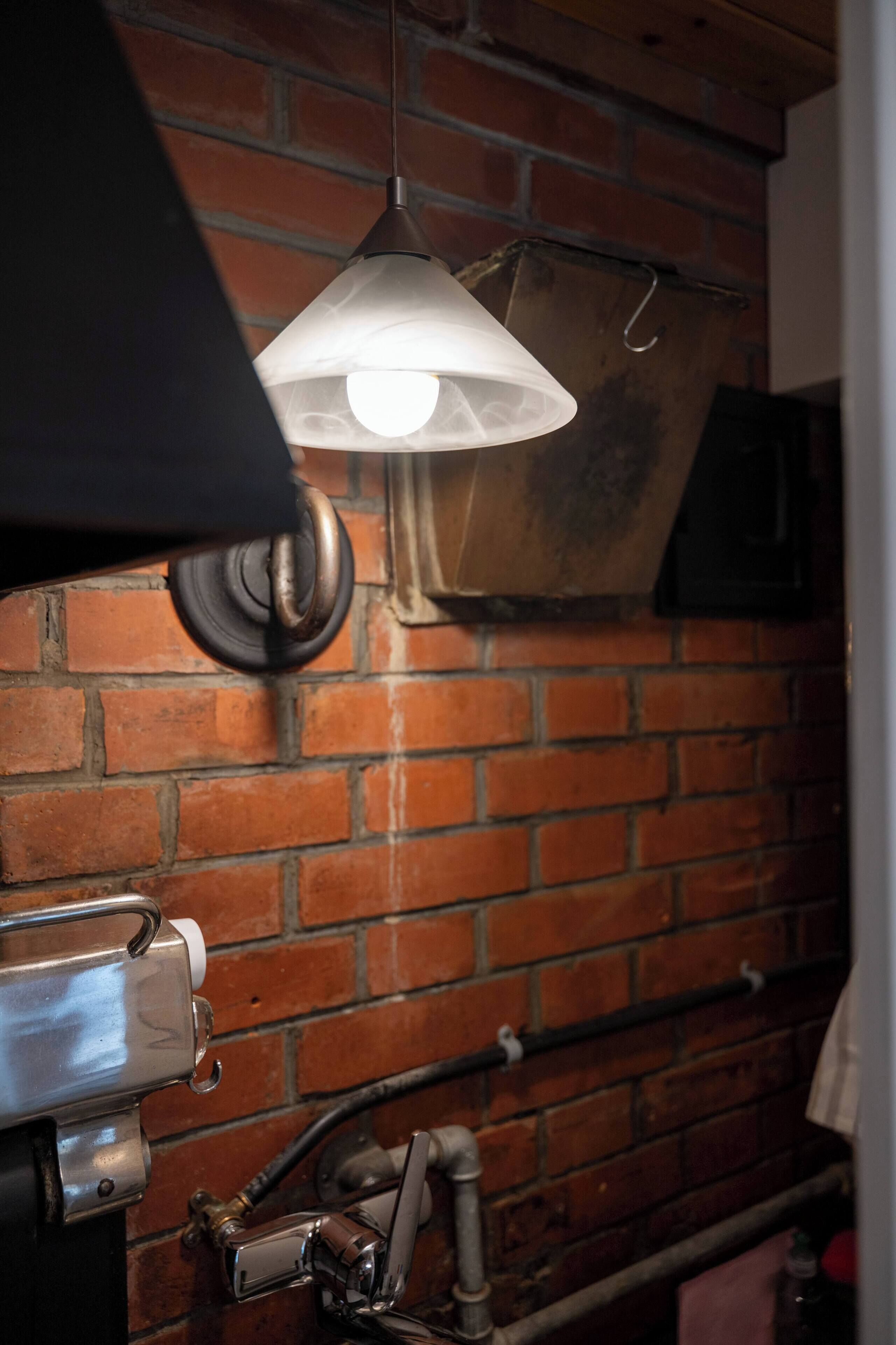 A brick wall with a hanging light fixture and a metal structure.