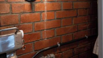A brick wall with a hanging light fixture and a metal structure.
