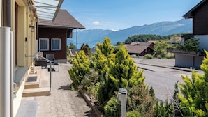 Un quartier résidentiel avec une maison dotée d’un balcon, offrant une vue dégagée sur les montagnes et comprenant une allée pavée.