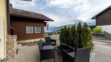 An outdoor seating area with wicker furniture, a stone wall, and a view of mountains in the background.