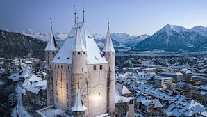 Un château historique doté de nombreuses tours et surplombant un paysage enneigé.