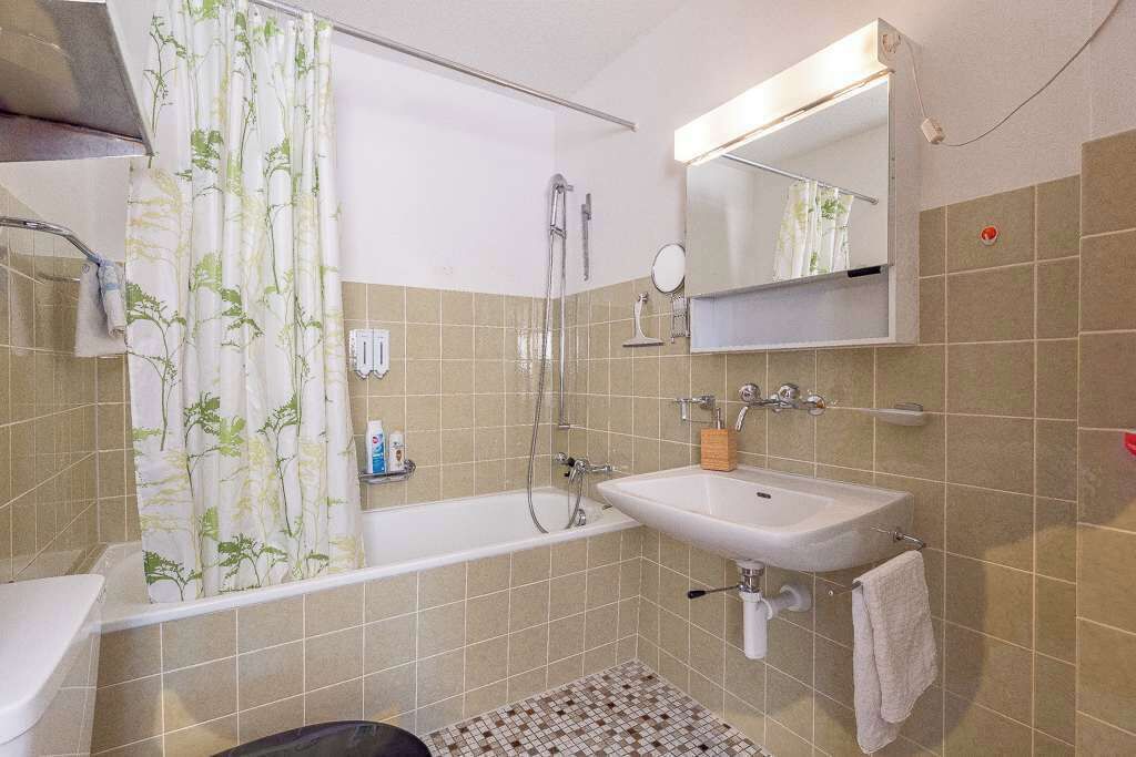 A bathroom with a bathtub, a sink, a shower, and a mirror.