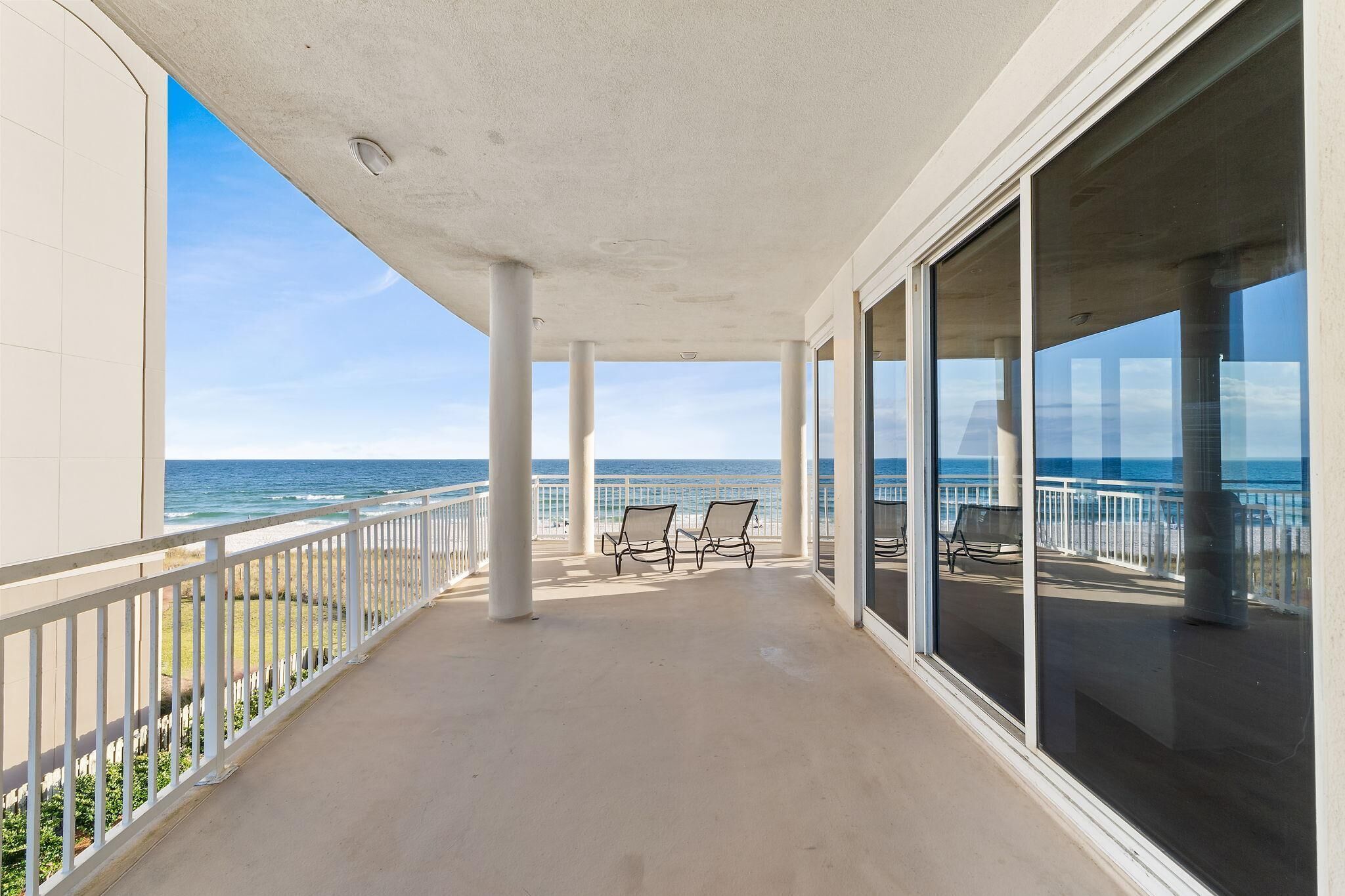 Un balcon avec deux chaises, une balustrade et une vue sur l’océan.