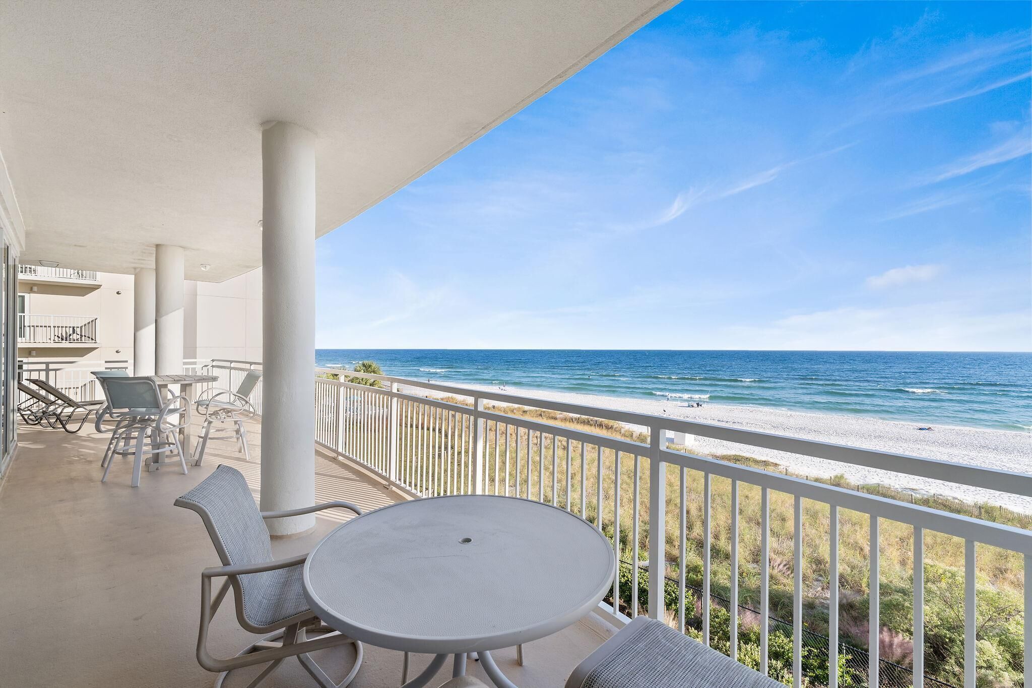 A balcony with a view of the beach and ocean.