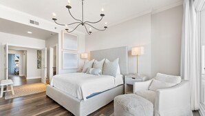Quarto moderno com uma cama grande, mesas de cabeceira, um lustre e vista para o exterior.