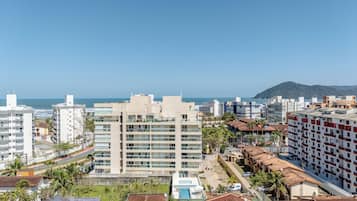 Paisagem costeira com edifícios modernos e tradicionais, céu claro e vista para o mar.
