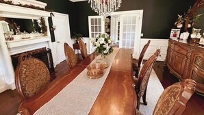 Un comedor con mesa de madera, sillas, una araña y una chimenea.