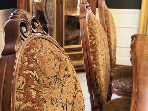 A close-up of ornate wooden furniture with intricate carvings and a patterned fabric upholstery.