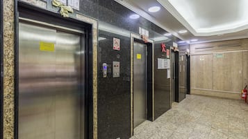 A corridor with elevators, each marked with a number and a sign indicating a no-smoking policy.