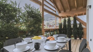 A dining area with a table set for breakfast, including bowls, cups, and pastries, overlooking a mountainous landscape. - Refined Alpine Escape near Mont Blanc (MEGEVE)