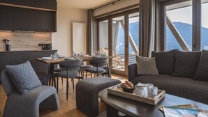 A modern living room with a sofa, chairs, and a dining area with a table and chairs. - Family Retreat in Peisey-Vallandry (Plan Perisey)