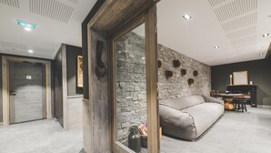 Ein modernes Wohnzimmer mit Steinwand, einer Couch, einem Holztisch und einem Kamin.