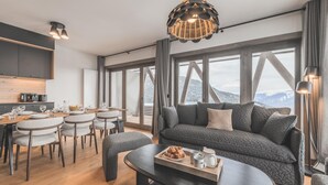 Ein modernes Wohnzimmer mit einer Couch, einem Essbereich und großen Fenstern mit Blick auf die Berge.