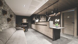 A modern interior with a stone wall, a wooden reception desk, a sofa, and a dining area. - Apartment in Peisey-Vallandry for 10 (Plan Perisey)