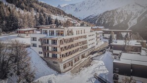 A modern building with multiple floors, surrounded by snow-covered mountains and trees. - Apartment in Peisey-Vallandry for 10 (Plan Perisey)