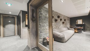 A modern living room with a stone wall, a sofa, and a wooden-framed sliding door. - Apartment in Peisey-Vallandry for 10 (Plan Perisey)