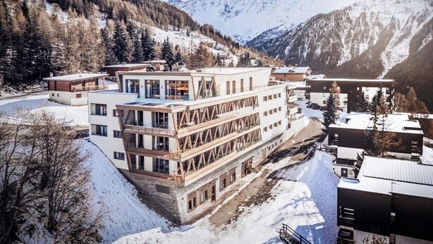 A modern hotel with a multi-story structure, surrounded by snow-covered mountains and trees. - Apartment in Peisey-Vallandry for 10 (Plan Perisey)