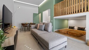 A modern living room with a grey sofa, a wooden slatted ceiling, and a dining area with a table and chairs. - Studio Palace B by Homie (Funchal)