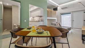 A modern dining area with a wooden table, chairs, and a breakfast setting. - Studio Palace B by Homie (Funchal)