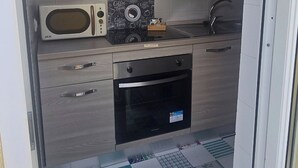 Cozinha compacta com micro-ondas, forno e painel decorado com tema de café.