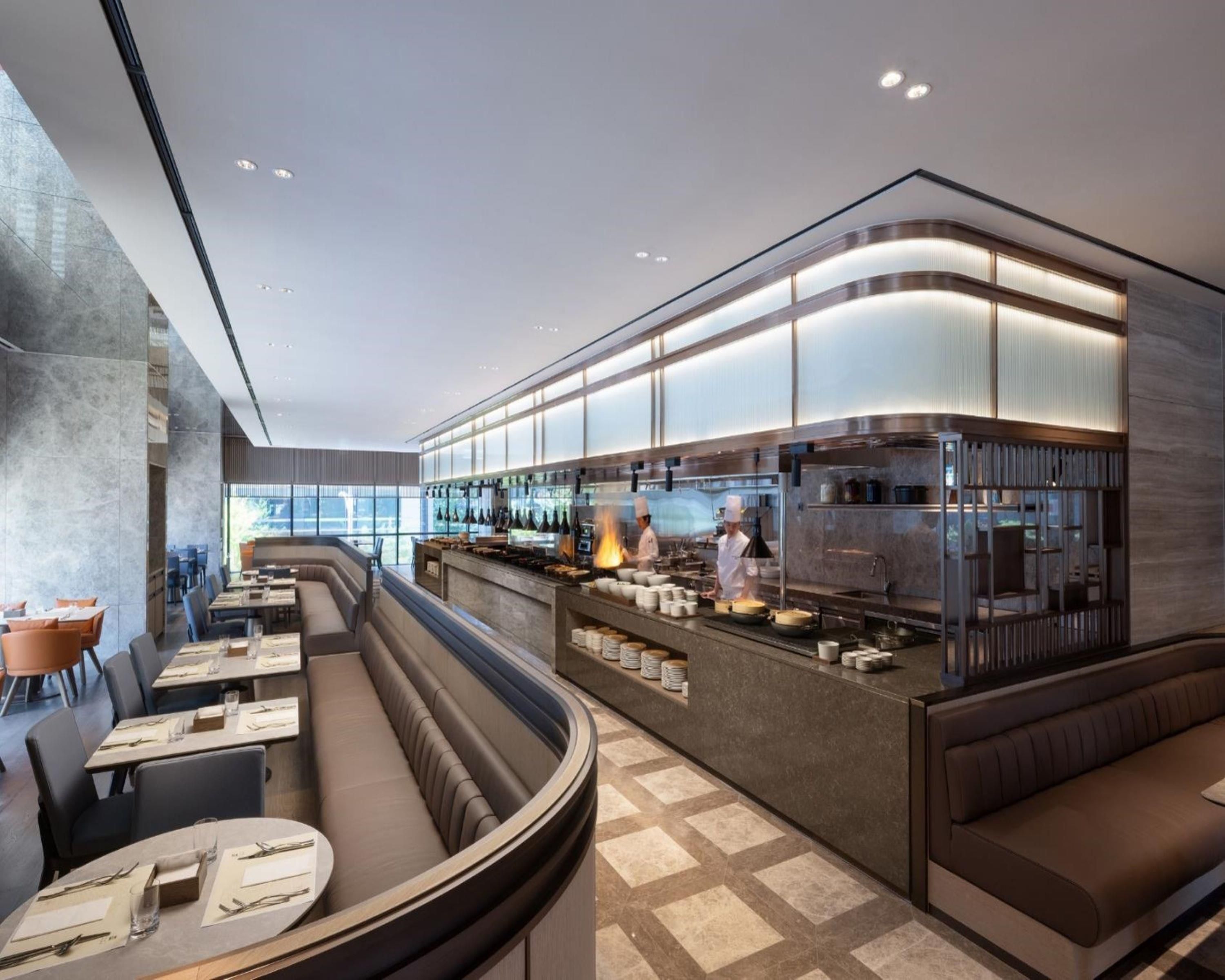A modern restaurant with a curved seating area, a bar, and a kitchen visible.