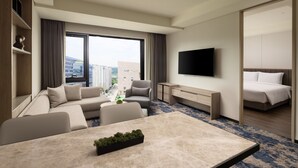 Una habitación de hotel moderna con sofá, televisión de pantalla plana, cama y escritorio.