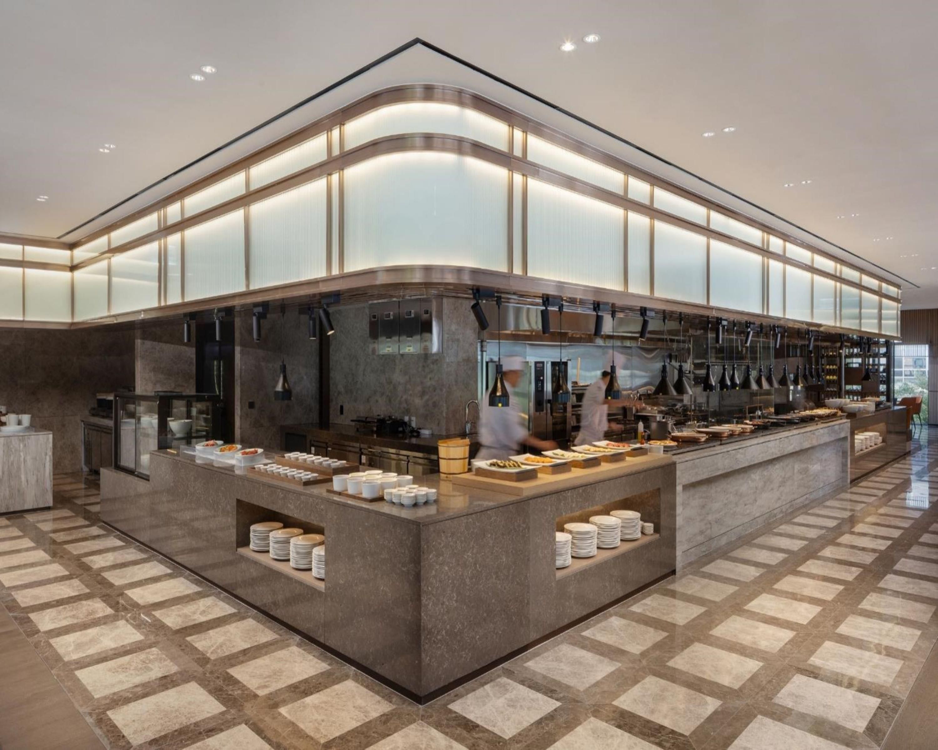 A modern kitchen with a central island, equipped with various appliances and a buffet setup.