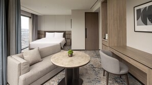 Una habitación de hotel moderna con cama, sofá, mesa redonda y una silla.