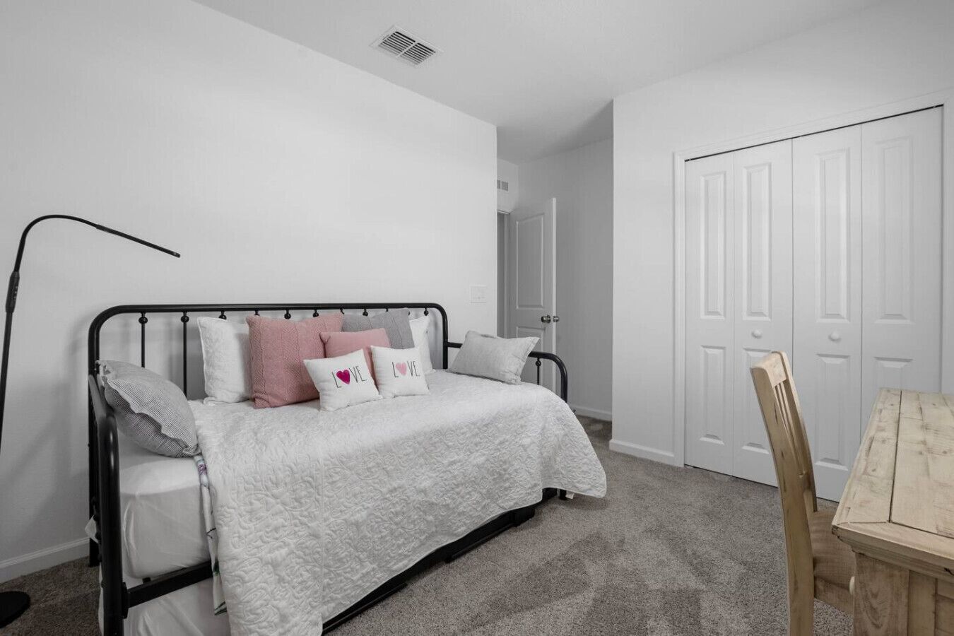 A bedroom with a bed, a bedside table, a chair, and a door.