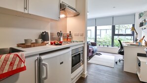 Cozinha moderna com armários brancos, forno embutido e uma grande janela que oferece luz natural.