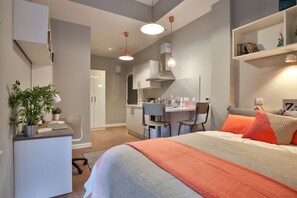 A modern bedroom with a bed, desk, and kitchenette. - Student Only The Ballet School (Glasgow)