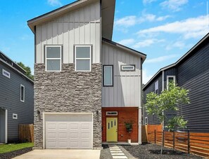 Ein zweistöckiges Haus mit Garage, einer Steinfassade und einem kleinen Vorgarten mit Baum.