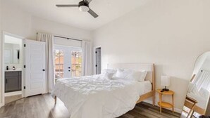 Une chambre à coucher avec un lit, un ventilateur de plafond, une petite table et un miroir.