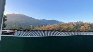 A view from a window overlooking a mountain range with autumn foliage. - The Lipton View Inn (Bandarawela)