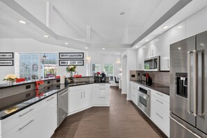 Une cuisine moderne avec des meubles blancs, des appareils en acier inoxydable et un îlot central.