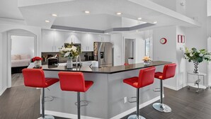A modern kitchen with a central island, bar stools, and a dining area. - Oasis: Spacious 4BR Pool Home in Inverness (Inverness)