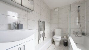 A modern bathroom with a white sink, toilet, and bathtub. - Stylish 4BR Home WiFi FreeParking (Thornton Heath)