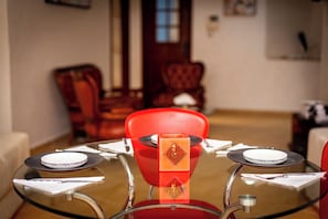 A dining table with a glass top, surrounded by red chairs, and a decorative orange block in the center. -  apartment in Tanger for your stay (Tanger)