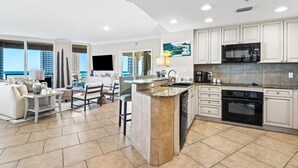 A modern kitchen with white cabinets, a black microwave, and a built-in oven. - Portofino Island Resort 4-704 (Pensacola Beach)