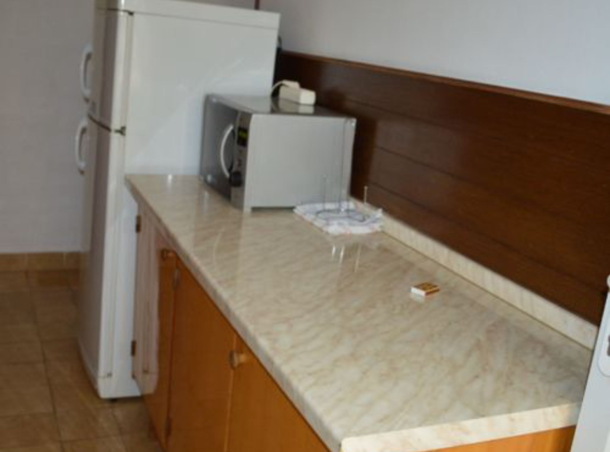 A kitchen with a white refrigerator, a microwave, and a small table with a placemat.