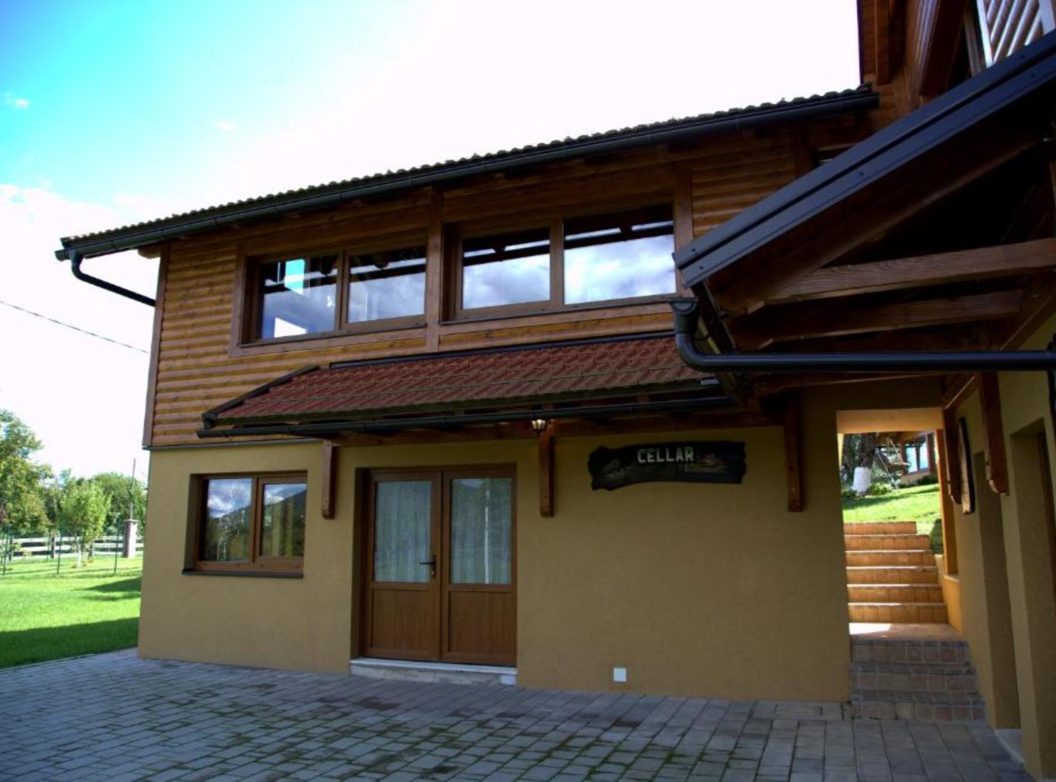 A two-story building with a wooden facade, a tiled roof, and a sign that reads "CELLAR".