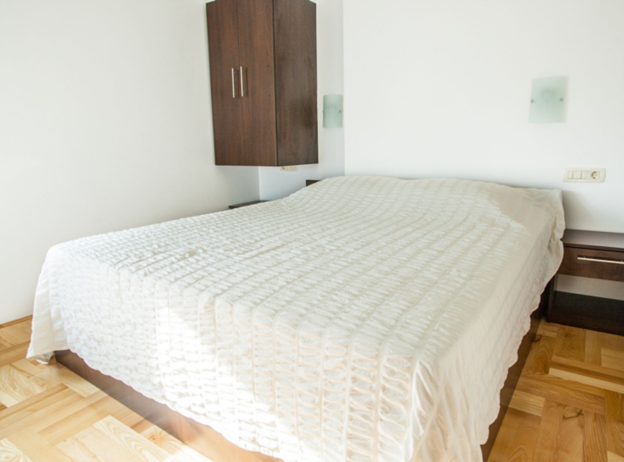 Une chambre à coucher avec un grand lit, un plancher en bois et une armoire en bois foncé.