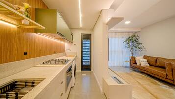 Una cocina moderna con horno integrado, lavadora y comedor con sofá y mesa de centro.